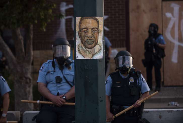 Bi polizia Minneapolisen, Geoger Floyd gogoratzen duen afitxa baten alboan  (Stephen MATUREN I AFP)
