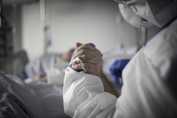 Un paciente agarra la mano de una profesional sanitaria en el Hospital de Gurutzeta.     (Andoni LUBAKI I FOKU)