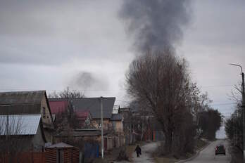 Una persona camina mientras una gran columna de humo se eleva cerca de la ciudad de Hostomel y del aeropuerto Antonov, en el noreste de Kiev. 