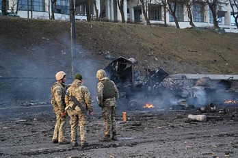 Soldados ucranianos contemplan un vehículo destruido en Kiev. 