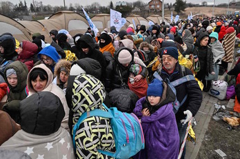Refugiados hacen cola para ser trasladados a una estación de tren después de cruzar la frontera de Ucrania con Polonia, en Medyka.