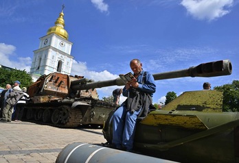 Un hombre lee apoyado en un fragmento de un cohete Tochka-U en una exposición al aire libre de equipos rusos destruidos en el centro de Kiev este 1 de junio.