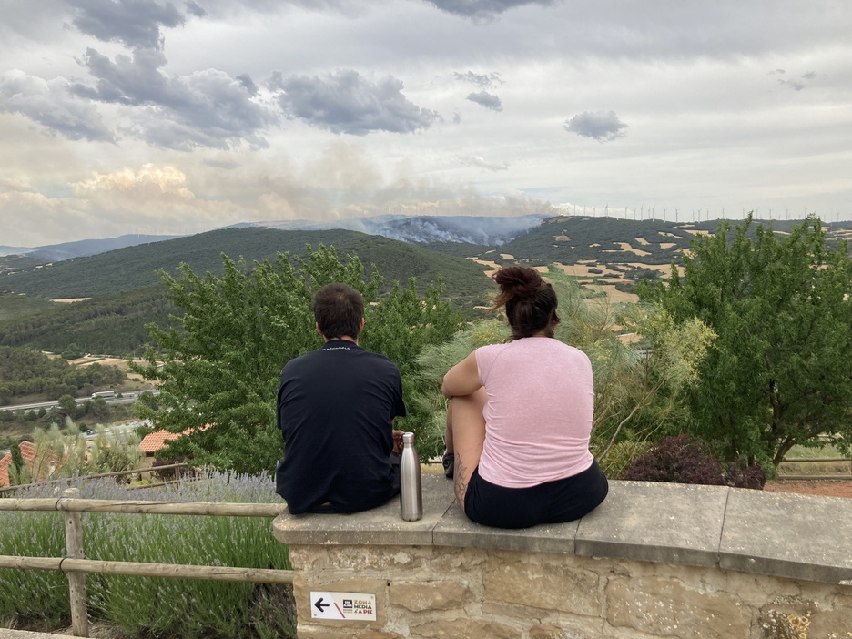 Dos personas observan desde Puiu la destrucción que dejan las llamas. Dos personas observan desde Puiu la destrucción que dejan las llamas.