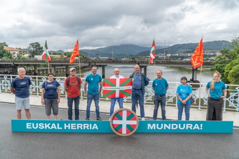 Gure Eskuko ordezkariek Tourrean banatuko duten ikurriña eredua erakutsi dute Avenida zubian eginiko agerraldian.