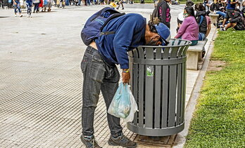 Un hombre rebusca en una papelera en una calle de Buenos Aires.