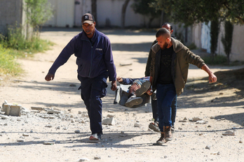 Varios hombres llevan el cuerpo de un hombre tras un bombardeo israelí en el campo de refugiados de Nuseirat.
