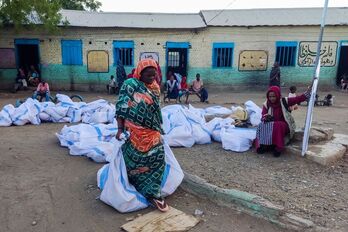 Mujeres desplazadas en Sudán trasladan sus posesiones recogidas en sábanas.