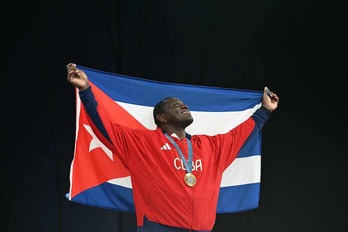 Mijaín López celebra su quinto título olímpico consecutivo con la bandera cubana y la medalla de oro.