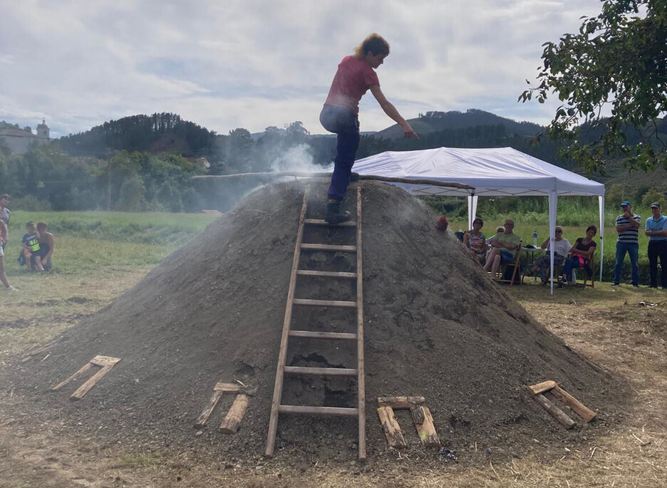 Lastoz eta lurrez estaltzen dute ondoren egurra, bertan egosi dadin Lastoz eta lurrez estaltzen dute ondoren egurra, bertan egosi dadin